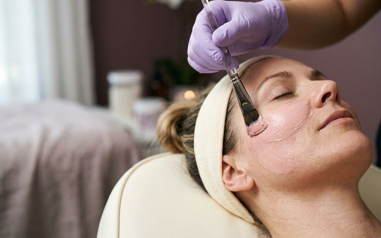 Treatment mask being applied to a client’s face with a flat brush