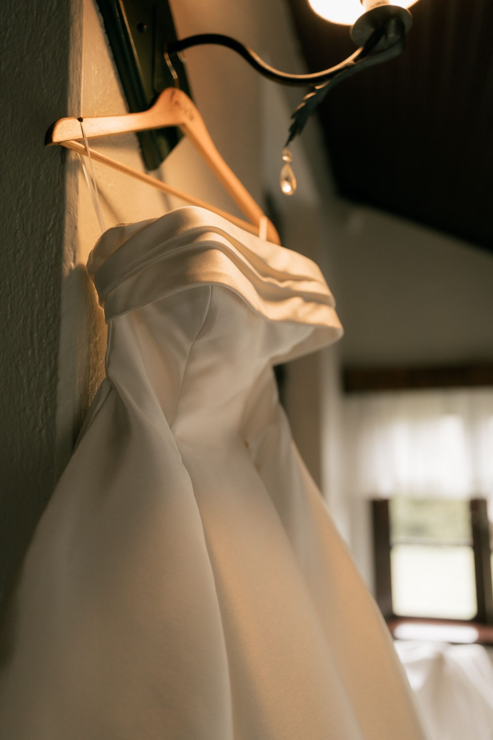 A wedding dress hanging in soft natural light, detail shot