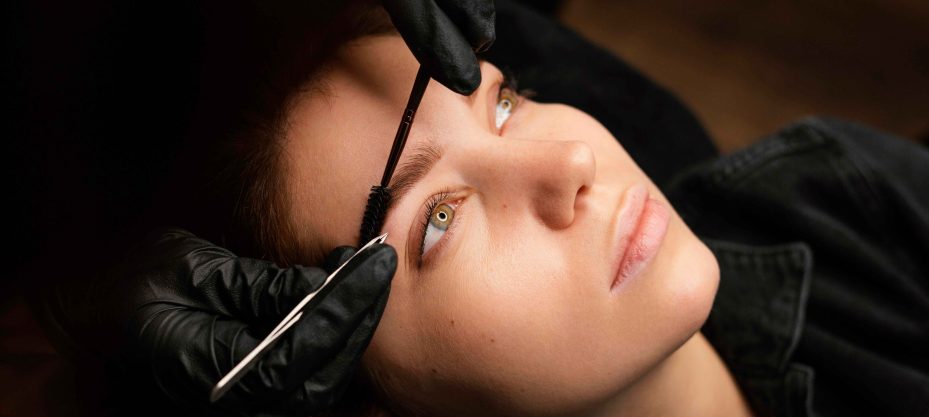 high-angle-female-clinician-doing-eyebrow-treatment-female-customer