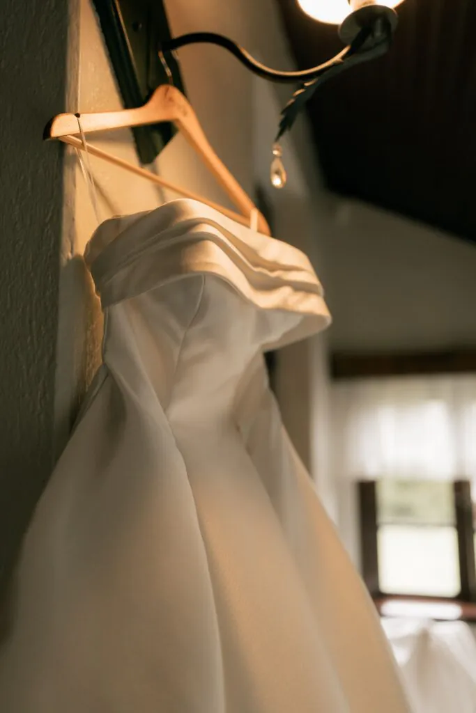 A wedding dress hanging in soft natural light, detail shot